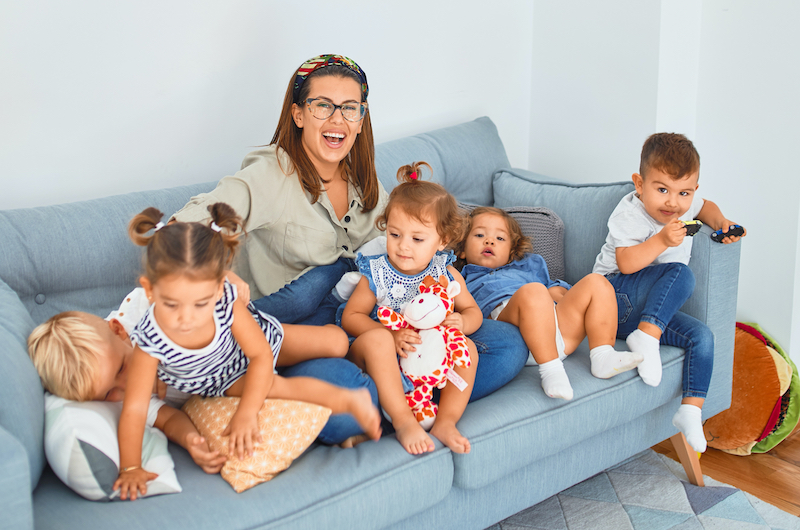 Frau mit vielen kleinen Kindern auf Sofa