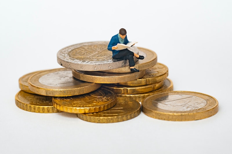 Kleine Figur sitzt auf Münzgeld